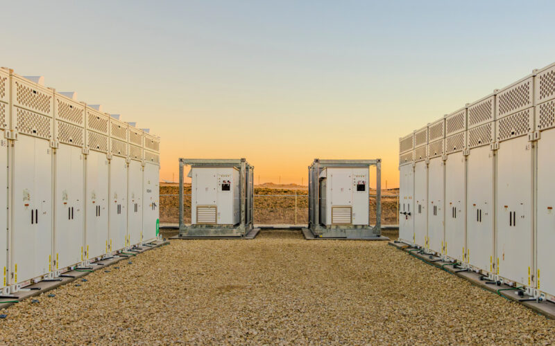 Rows of white battery energy storage containers at a Texas project site at sunset